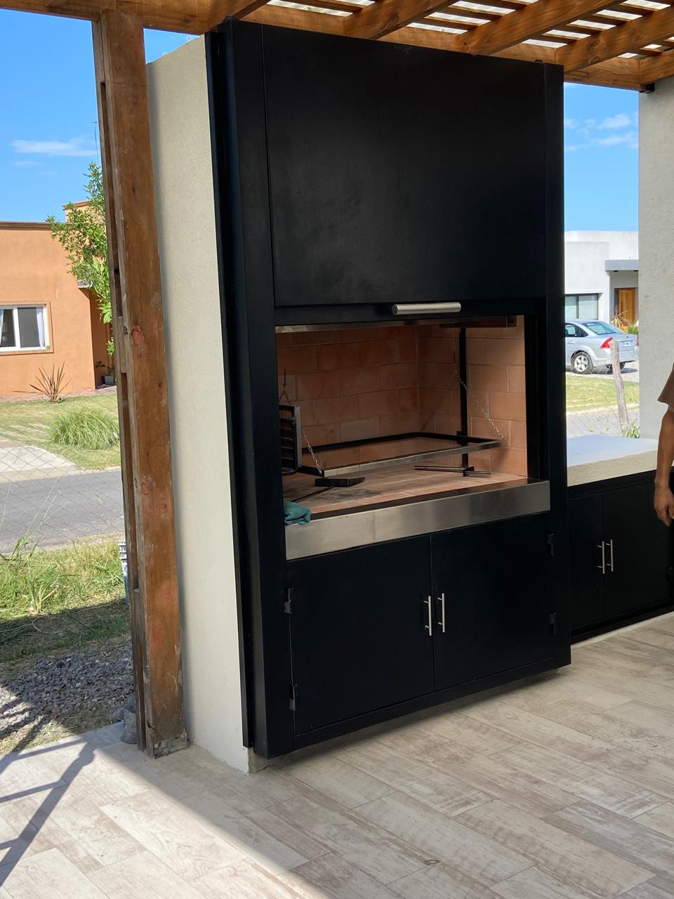 Frente de parrilla con hogar a leña instalado en quincho exterior